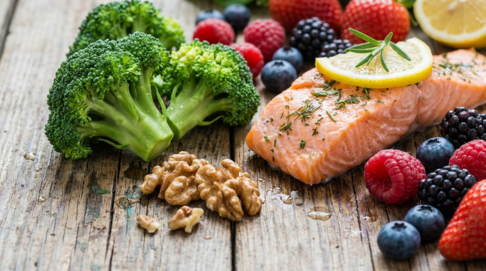 Eine detaillierte Nahaufnahme von frischen, bunten Lebensmitteln wie Brokkoli, Lachs, Walnüssen und Beeren auf einem rustikalen Holztisch, sanft und appetitlich beleuchtet.