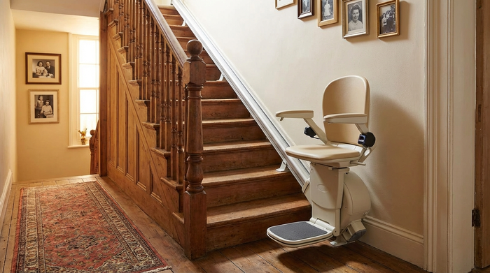 Ein Treppenlift ist an einer hölzernen Treppe im Flur montiert, der Sitz ist beige und platzsparend hochgeklappt