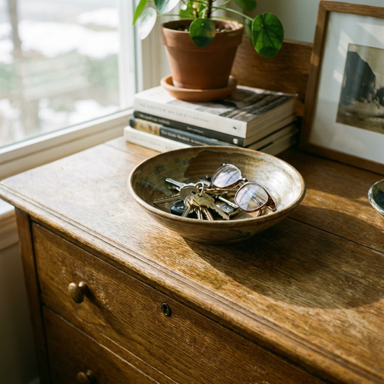 Schlüsselbund und Brille in einer gut sichtbaren Schale auf einer Holzkommode.