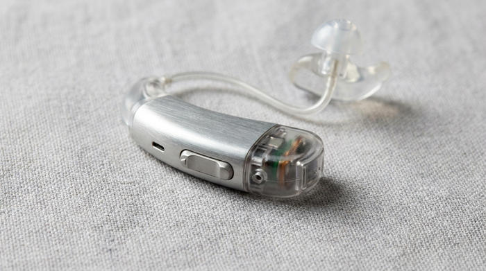 Modernes Hinter-dem-Ohr Hörgerät (HdO) liegt auf hellem Untergrund, Details von Gehäuse und Schallschlauch sichtbar.