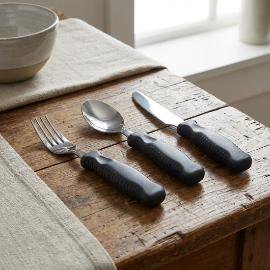 Spezialbesteck mit verdicktem Griff auf einem Tisch.