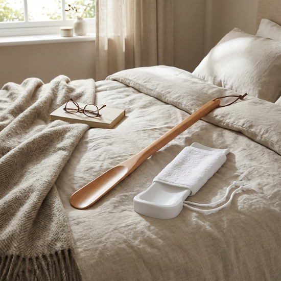 Strumpfanziehhilfe und Schuhlöffel liegen bereit auf dem Bett
