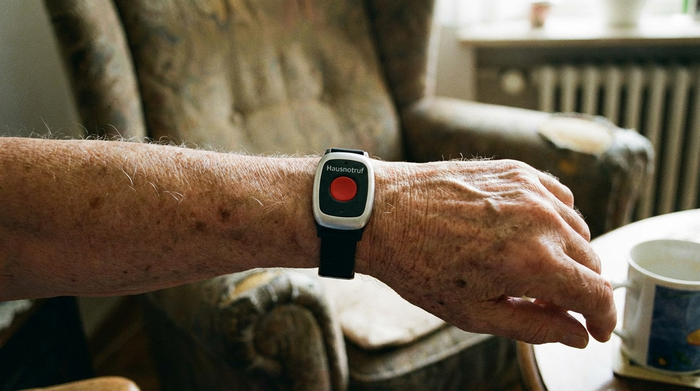 Hausnotruf-Armband am Handgelenk eines Seniors in Nahaufnahme
