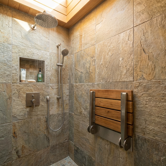 Ein fest montierter Duschsitz an der Wand einer gefliesten Dusche.