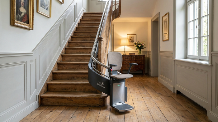 Moderner Treppenlift an einer Holztreppe in einem gepflegten Flur.