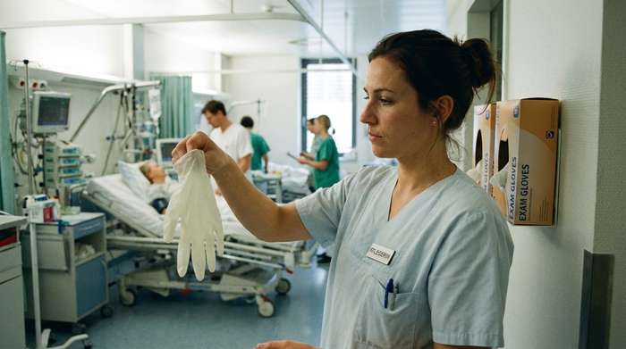 Pflegerin entnimmt frische Handschuhe aus einem Karton