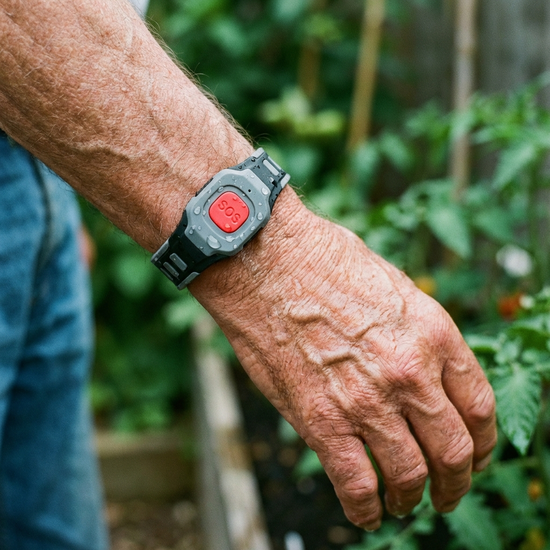 Wasserdichter Hausnotruf-Knopf als Armband am Handgelenk eines Seniors
