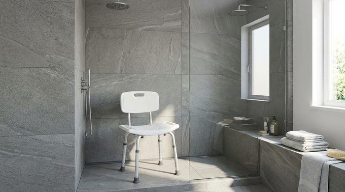 Stabiler, weißer Duschstuhl mit rutschfesten Gummifüßen in einer modernen Dusche.