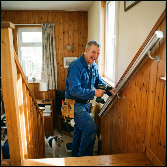 Freundlicher Handwerker montiert eine Treppenliftschiene an der Wand