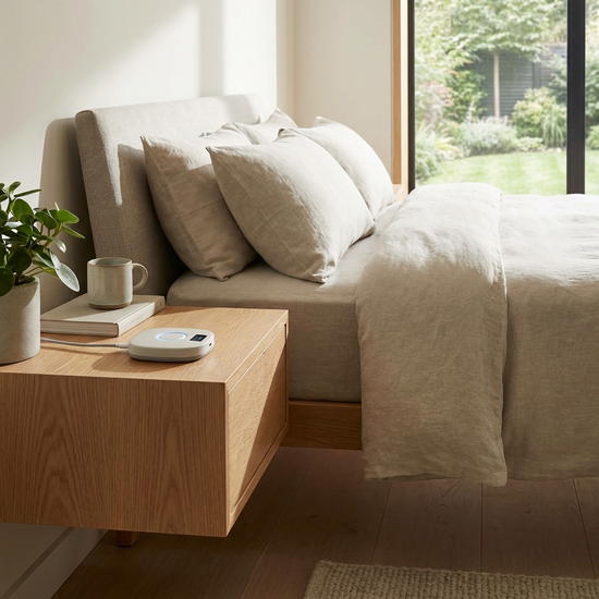 Moderner Hausnotruf-Sender auf einem Nachttisch neben einem Bett