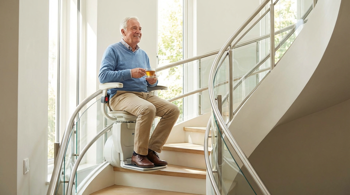 Senior fährt entspannt und sicher mit einem modernen elektrischen Treppenlift in die obere Etage seines Hauses