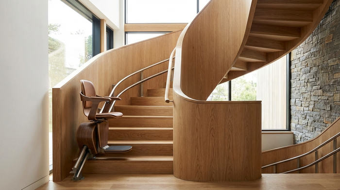 Moderner Treppenlift an einer geschwungenen Holztreppe