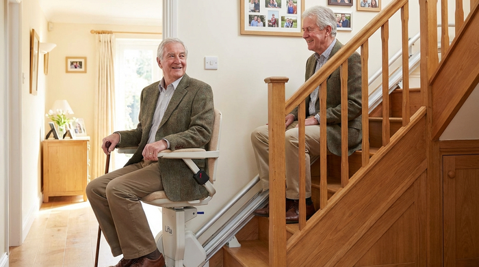 Senior fährt sicher mit einem Sitz-Treppenlift die Treppe hinauf