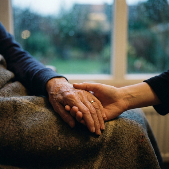 Zwei Hände halten sich tröstend vor einem unscharfen Hintergrund