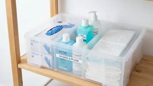 Ordentlich sortierte Box mit Einmalhandschuhen, Desinfektionsmittel und Bettschutzeinlagen.