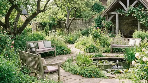 Ruhiger Hospizgarten mit Bänken, umgeben von grünen Pflanzen und Blumen