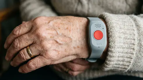 Nahaufnahme eines Hausnotruf-Armbands am Handgelenk einer Seniorin