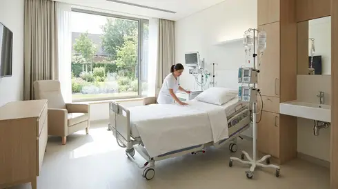 Krankenhausbett mit Infusionsständer in einem sauberen Patientenzimmer