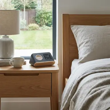 Modernes Hausnotruf-Gerät auf einem Nachttisch neben einem Bett