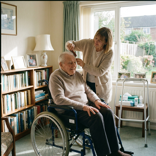 Pflegebedürftiger Senior wird von Angehöriger liebevoll zuhause versorgt