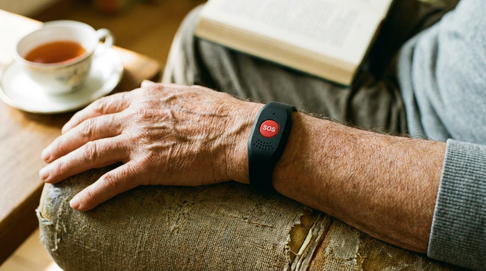 Hausnotruf-Armband am Handgelenk eines Seniors