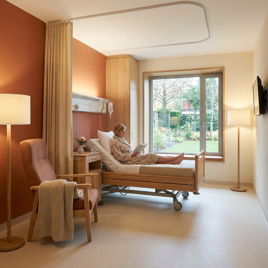 Modernes Krankenhauszimmer mit wohnlicher Einrichtung und warmen Farben