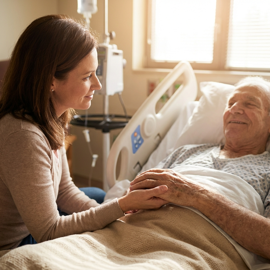 Tochter hält sanft die Hand ihres Vaters am Bett