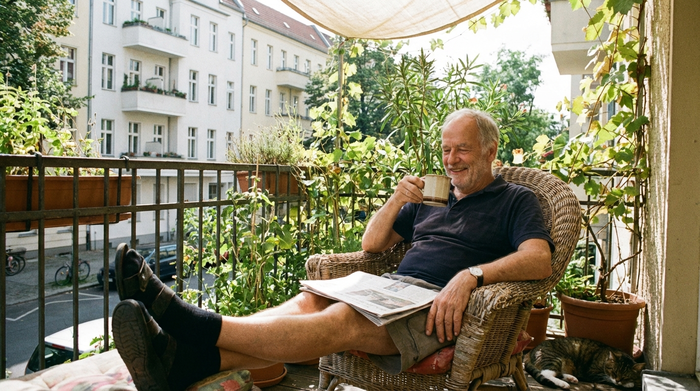 Ein entspannter Angehöriger sitzt auf dem Balkon und trinkt in Ruhe eine Tasse Kaffee.