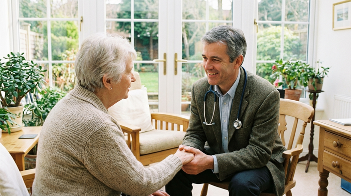 Mitfühlender Arzt im Gespräch mit einer älteren Patientin in einer hellen Praxis