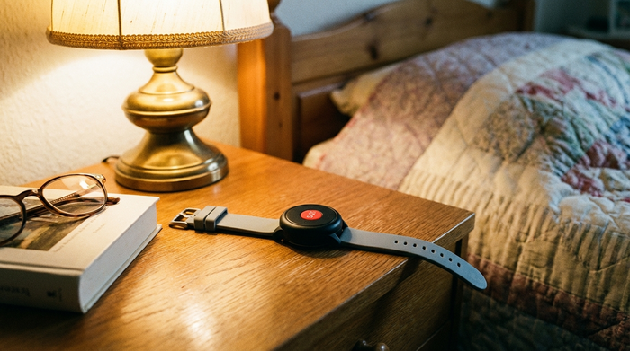 Hausnotruf-Sender als Armband auf einem Nachttisch.