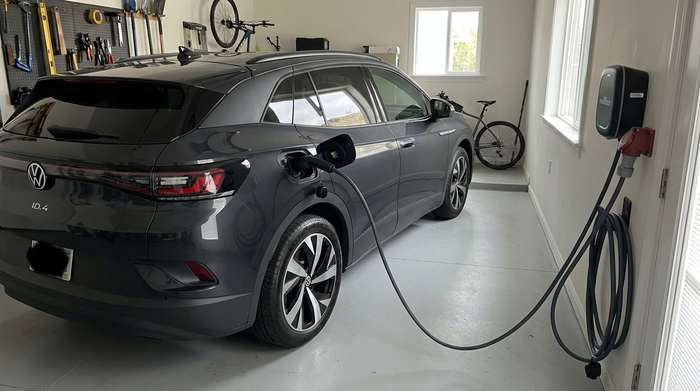 Elektromobil steht sicher in einer Garage und ist über ein Kabel mit einer Wandsteckdose verbunden