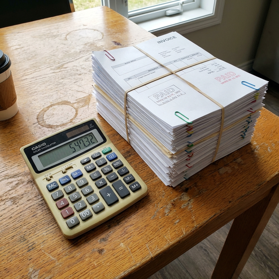 Ordentlicher Stapel mit Rechnungen und ein Taschenrechner auf einem Holztisch
