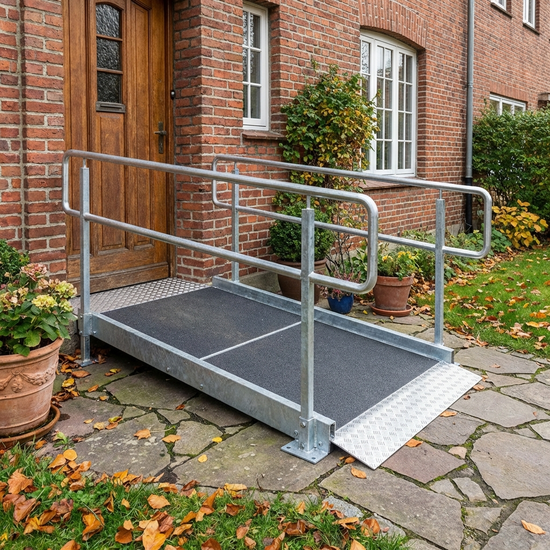 Fest installierte, flache Rollstuhlrampe aus Metall vor einer Haustür
