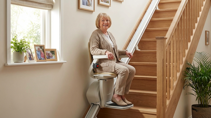 Zufriedene ältere Dame nutzt ihren fertig installierten Treppenlift und lächelt entspannt