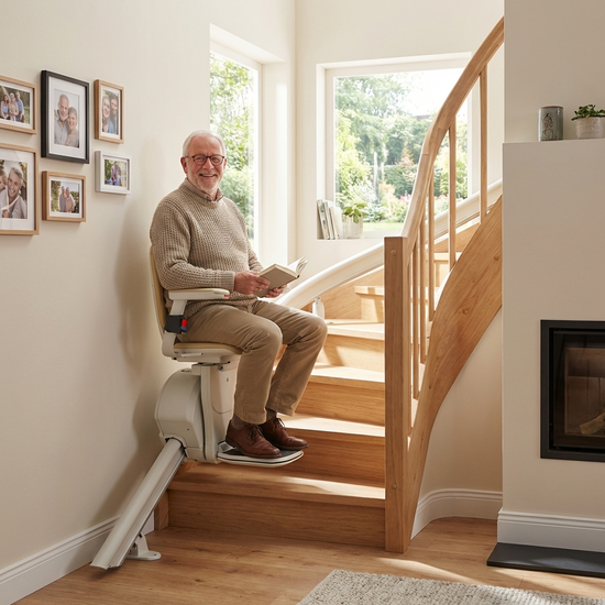 Ein Senior fährt sicher und entspannt mit einem Treppenlift die Treppe hinauf.