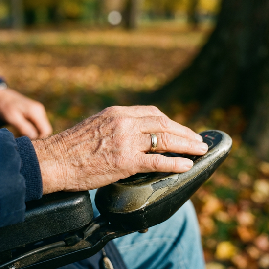 Nahaufnahme der Hand eines Seniors, die entspannt den Joystick eines Elektrorollstuhls bedient