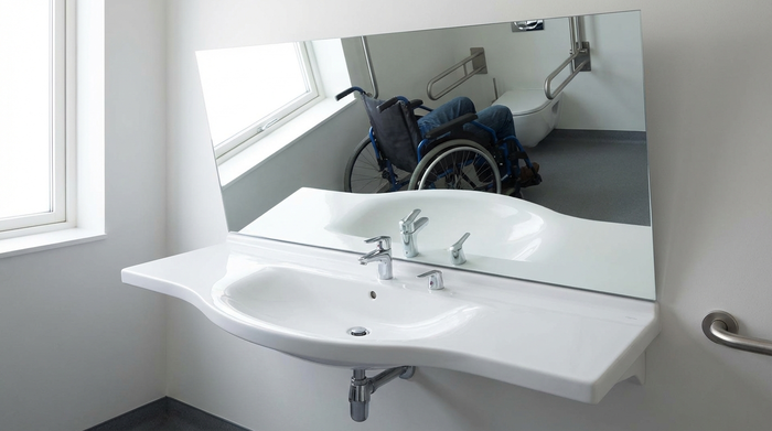 Detailaufnahme eines ergonomisch geformten, unterfahrbaren Waschbeckens mit großem Spiegel