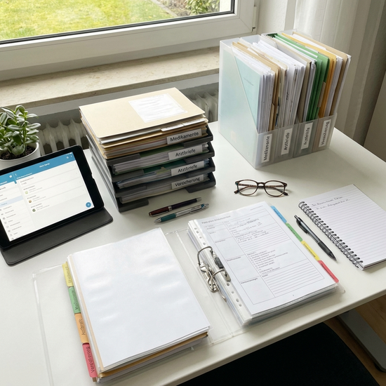 Übersichtlich sortierte Dokumente und Pflegeunterlagen auf einem Schreibtisch