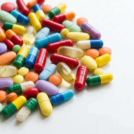 Verschiedene bunte Medikamentenkapseln und Tabletten auf einem sauberen weißen Tisch