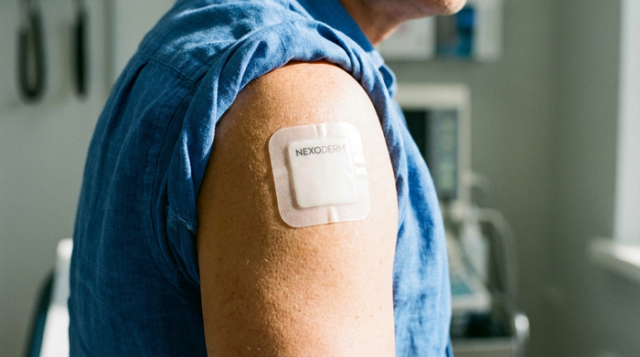 Ein helles, quadratisches Medikamentenpflaster auf dem Oberarm einer Person