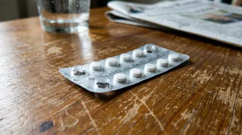 Nahaufnahme einer Blisterpackung mit kleinen weißen Tabletten auf einem Tisch