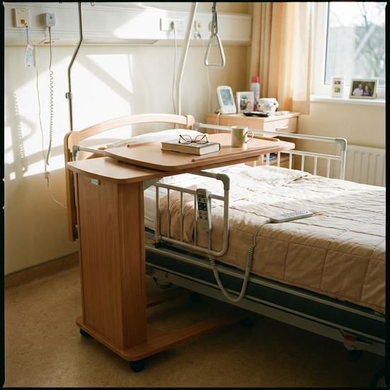 Nachttisch mit schwenkbarer Tischplatte neben einem Pflegebett