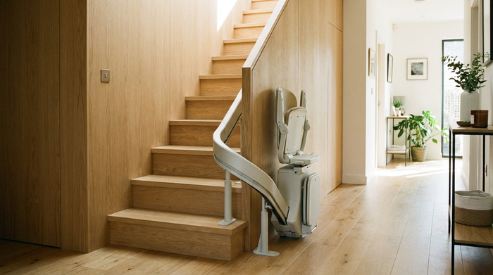 Ein moderner, unauffälliger Treppenlift an einer hellen Holztreppe in einem gepflegten Einfamilienhaus. Die Umgebung ist ordentlich und gut beleuchtet. Realistische Darstellung, keine Labels oder Texte.