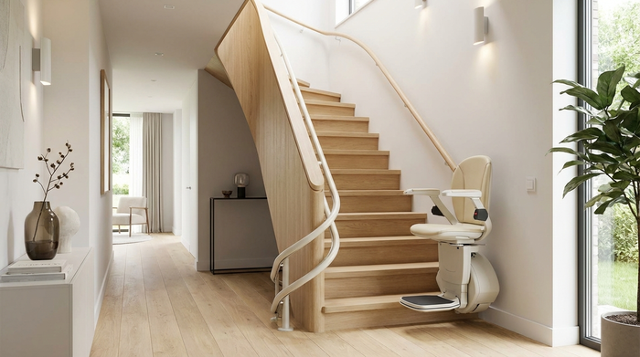 Ein moderner Treppenlift an einer geschwungenen Holztreppe in einem hellen, aufgeräumten Flur eines Einfamilienhauses. Hochwertige Ausstattung und saubere Umgebung.