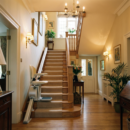 Ein eleganter Treppenlift gleitet sanft eine gut beleuchtete Holztreppe in einem gepflegten, wohnlichen Einfamilienhaus hinauf.