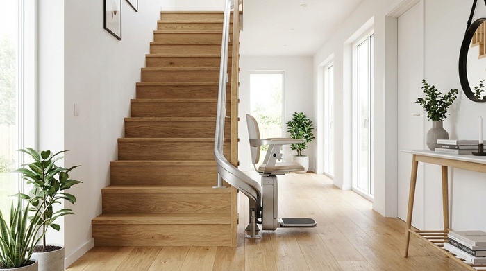 Ein eleganter, moderner Treppenlift ist an einer Holztreppe in einem hellen, aufgeräumten Flur installiert. Die Konstruktion wirkt sicher und fügt sich harmonisch in das gemütliche Zuhause ein.