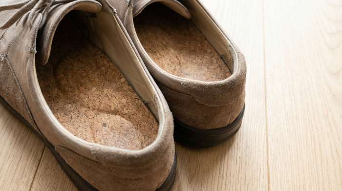 Nahaufnahme von passgenauen orthopädischen Einlagen in bequemen Senioren-Halbschuhen auf einem hellen Holzboden. Hochwertige Materialien, weiche Polsterung, fotorealistisch und sauber.