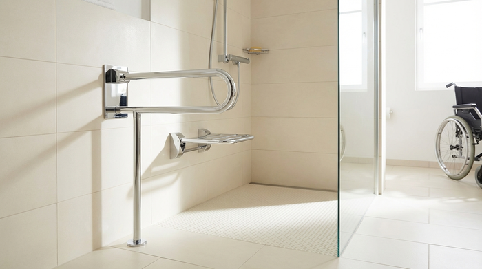 Eine moderne, ebenerdige Dusche in einem hell gefliesten, barrierefreien Badezimmer. Ein sicherer, verchromter Haltegriff und ein rutschfester Bodenbelag sind deutlich erkennbar.