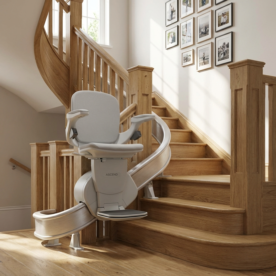 Eine Nahaufnahme eines eleganten Treppenlifts, der an einer geschwungenen Holztreppe in einem gepflegten Einfamilienhaus montiert ist. Der Sitz ist hellgrau und modern.