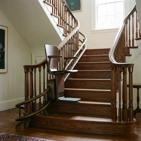 Ein eleganter, unauffälliger Treppenlift an einer geschwungenen Holztreppe in einem gepflegten Einfamilienhaus.